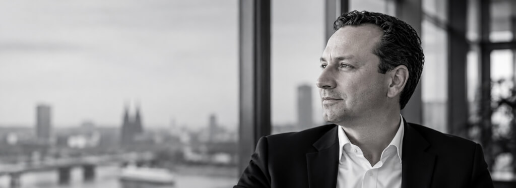 Hans J. Friedrich, Gründer von Go2Market Experts, blickt aus dem Fenster über die Stadt